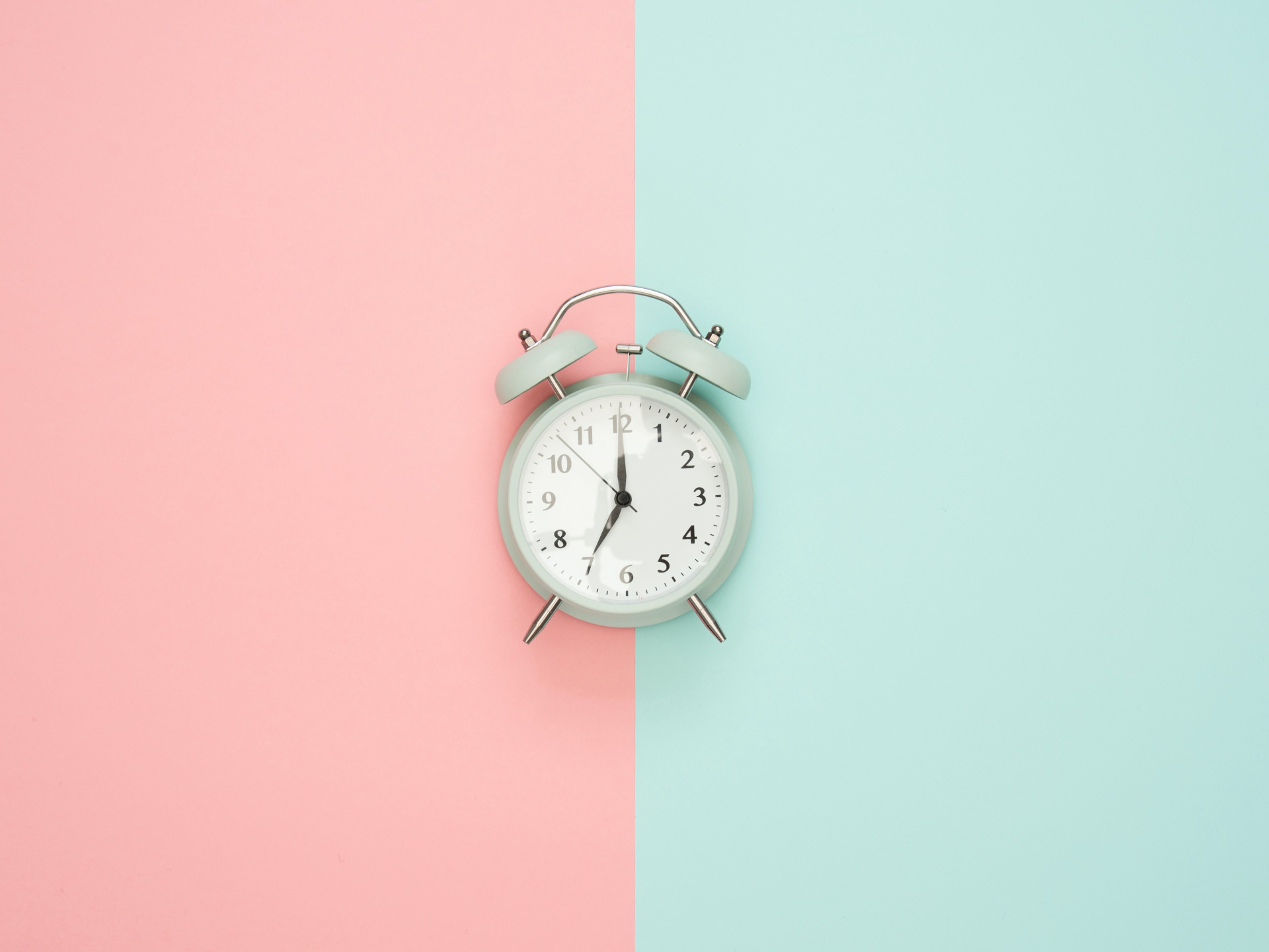 Old fashioned alarm clock over blue and pink background