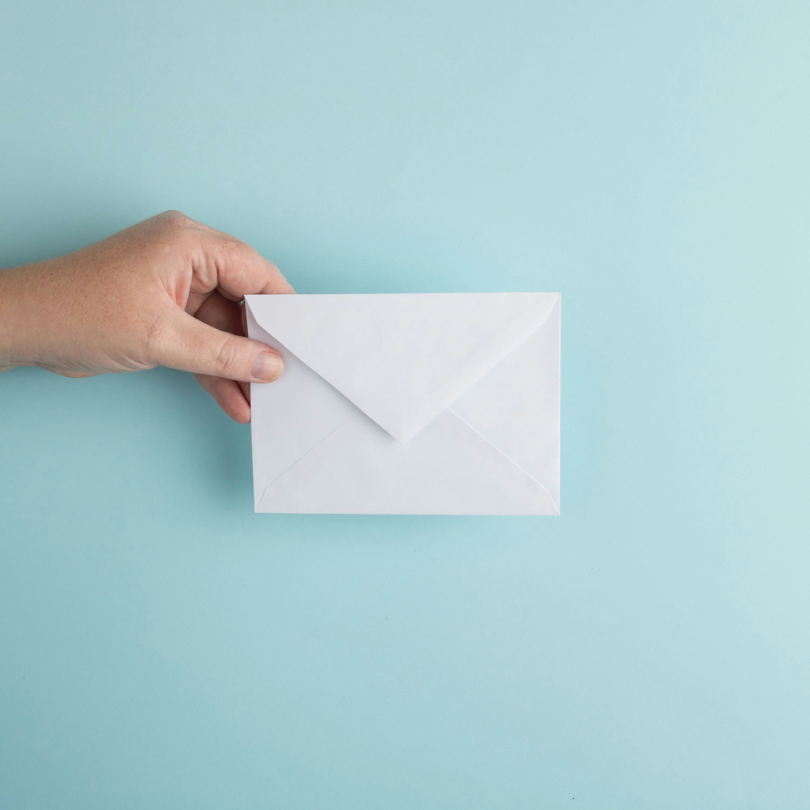 Hand holding a white envelope
